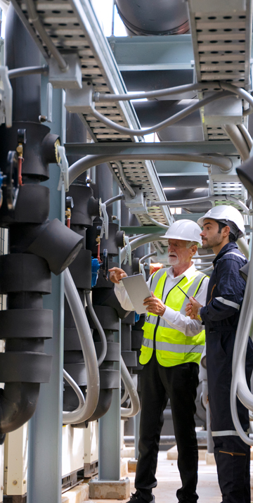 Two men inspecting black foam insulation installed pipe systems